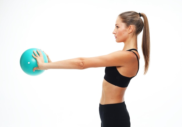 Jeune femme adulte en forme faisant de l'exercice de yoga avec ballon de gymnastique