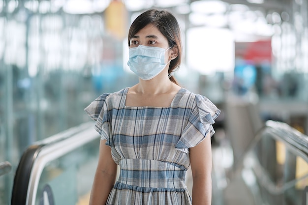 Jeune femme adulte portant un masque facial dans le terminal de l'aéroport