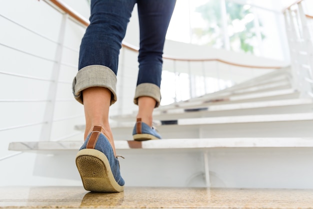 Jeune femme adulte en remontant les escaliers avec fond de sport de soleil.