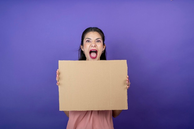 Jeune femme adulte surprise tenant un signe de texte gratuit sur fond de velours violet isolé