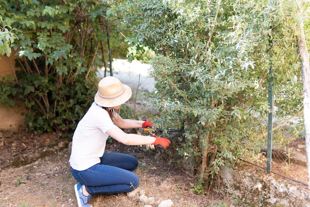 Jeune femme adulte travaillant dans le jardin à la maison pendant le week-end par une journée ensoleillée