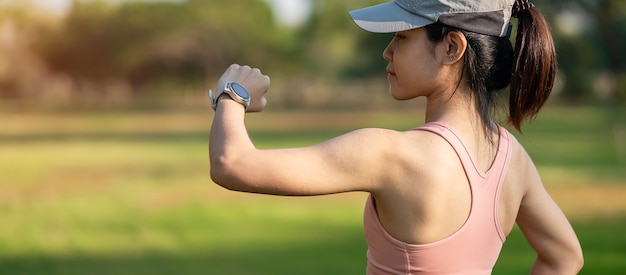 Jeune femme adulte vérifiant l'heure et la fréquence cardiaque cardio sur smartwatch sport pendant la course dans le parc en plein air, coureur femme jogging le matin. Exercice, technologie, style de vie et entraînement