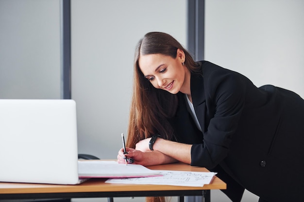 Jeune femme adulte en vêtements formels est à l'intérieur au bureau