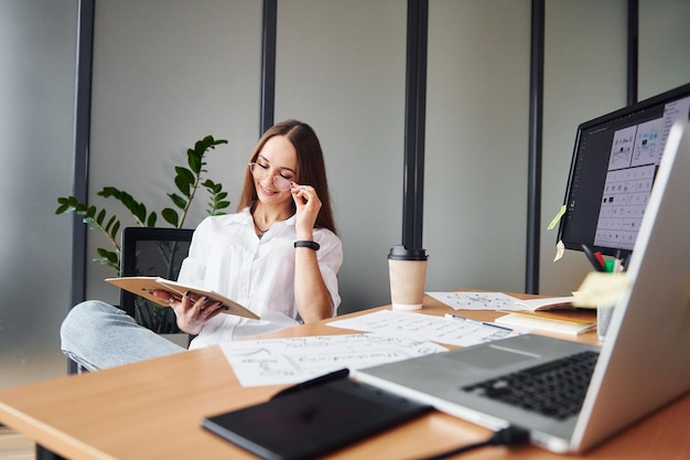 Jeune femme adulte en vêtements formels est à l'intérieur au bureau