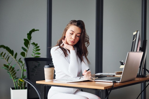 Une jeune femme adulte en vêtements formels est à l'intérieur du bureau