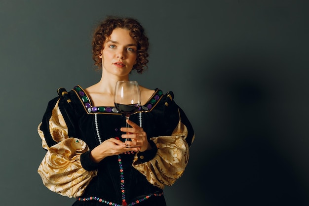 Photo une jeune femme adulte vêtue d'une robe médiévale tenant un verre de vin
