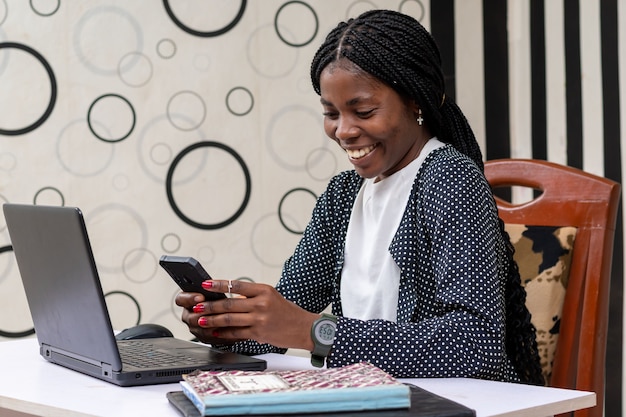 Jeune femme d'affaires africaine se sentant ravie des nouvelles qu'elle a vues sur son téléphone portable