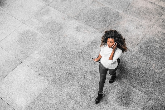 Jeune femme d&#39;affaires afro-américaine, parler au téléphone sur son chemin vers le lieu de travail.