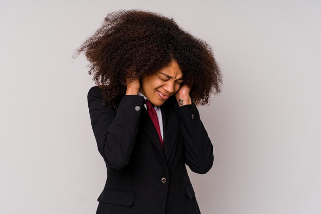 Jeune femme d'affaires afro-américaine portant un costume isolé sur blanc couvrant les oreilles avec les mains.