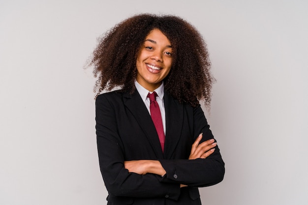 Jeune femme d'affaires afro-américaine portant un costume isolé sur blanc qui se sent confiant, croisant les bras avec détermination.