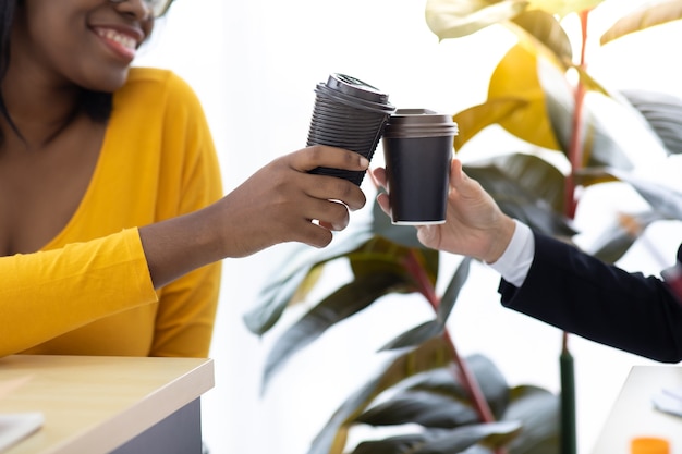 Une jeune femme d'affaires afro-américaine séduisante portant un masque protecteur empêche le virus covid-19 de boire du café noir