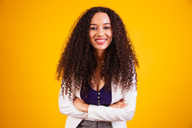 Jeune femme d'affaires afro avec les bras croisés souriant en regardant la caméra.