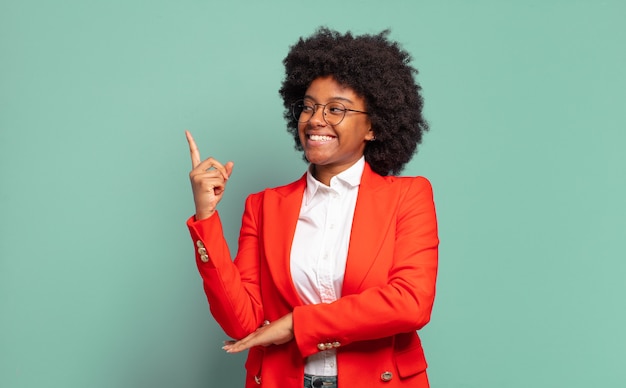 Jeune femme d'affaires afro contre le mur vert