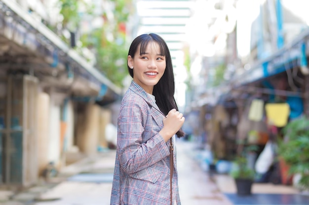 Jeune femme d'affaires asiatique confiante qui porte un blazer rayé marron et un sac à bandoulière.