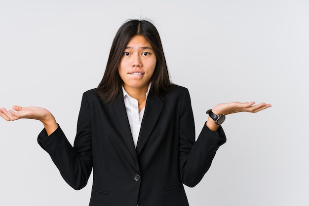 Jeune femme d'affaires asiatique confuse et douteuse en haussant les épaules pour tenir un espace de copie.