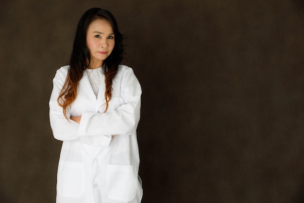 Jeune femme d'affaires asiatique en élégant manteau de robe blanche regardant la caméra et souriant sur fond gris foncé