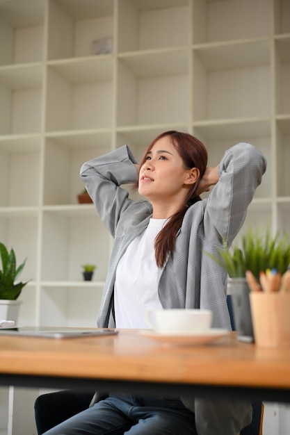 Jeune femme d'affaires asiatique ou employée de bureau étirant sa main de bras derrière sa tête