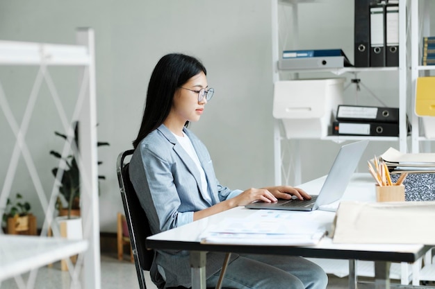 Jeune femme d'affaires asiatique ou étudiante travaillant en ligne sur un ordinateur portable