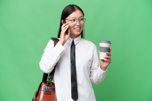 Jeune femme d'affaires asiatique sur fond isolé tenant du café à emporter et un mobile