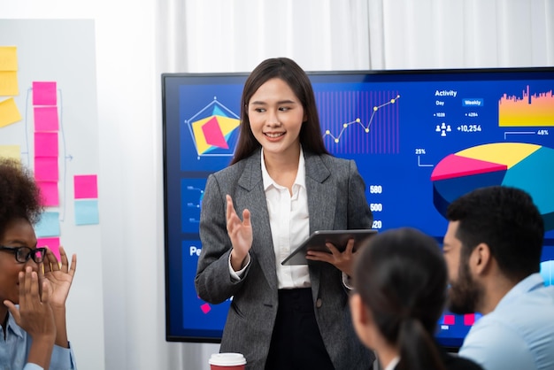 Jeune femme d'affaires asiatique présentant un tableau de bord d'analyse de données sur un écran de télévision lors d'une réunion moderne. Présentation d'affaires avec un groupe de gens d'affaires dans la salle de conférence Concord.