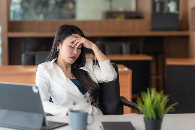 Une jeune femme d'affaires asiatique s'ennuie du stress de travailler au bureau.