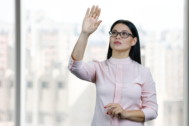 La jeune femme d'affaires asiatique touche l'écran virtuel invisible par sa main