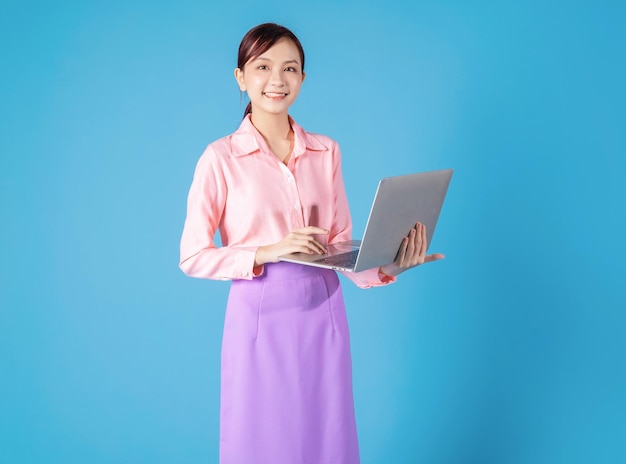 Jeune femme d'affaires asiatique utilisant un ordinateur portable sur fond bleu