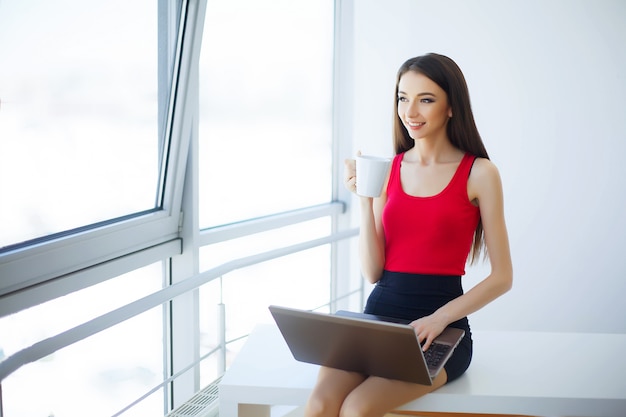 Jeune femme d'affaires assis à la table et travaille par ordinateur.