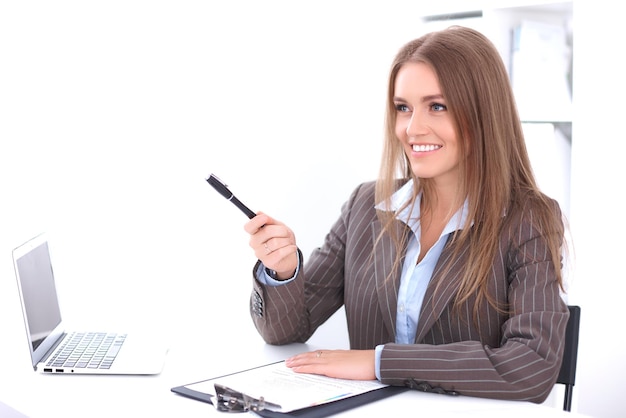 Jeune femme d'affaires assise au bureau sur fond de bureau.