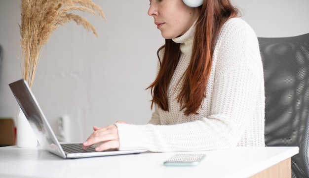 Jeune femme d'affaires assise au bureau travaillant en ligne sur un ordinateur portable