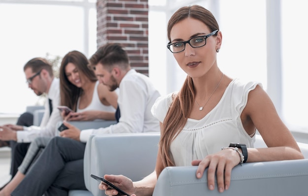 Jeune femme d'affaires assise dans la salle d'attente du bureau et de la technologie