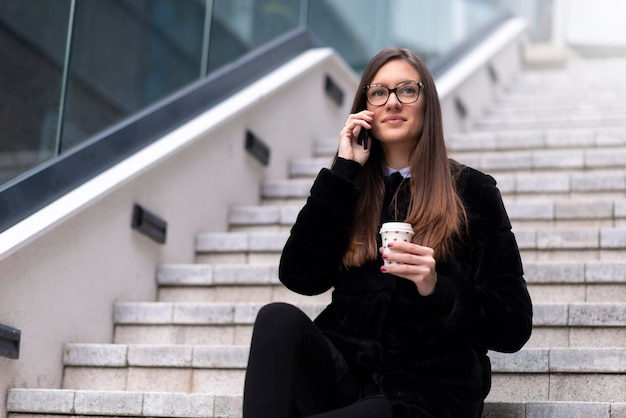 Jeune femme d'affaires assise et parlant au téléphone