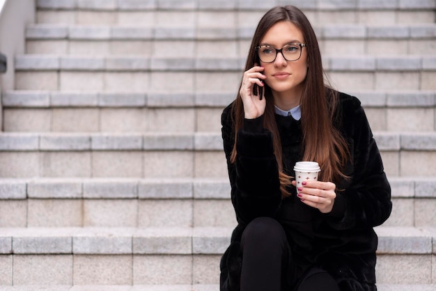 Jeune femme d'affaires assise et parlant au téléphone