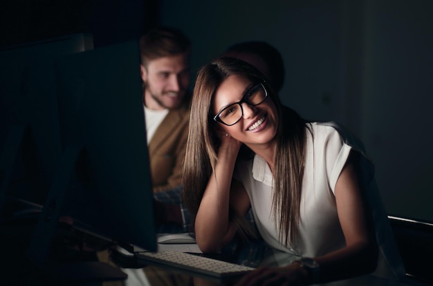 Jeune femme d'affaires assise à son bureau la nuit le concept d'heures supplémentaires