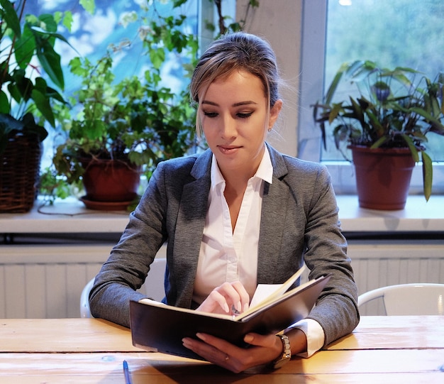 Jeune femme d'affaires assise à table dans un café et lisant