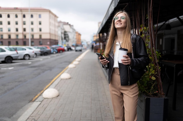 Jeune femme d'affaires au téléphone dans ses mains et une tasse de café