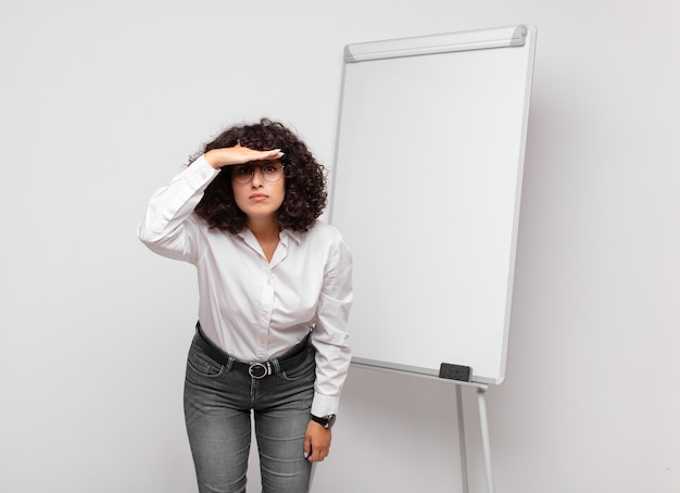 jeune femme d'affaires aux cheveux bouclés et un tableau blanc