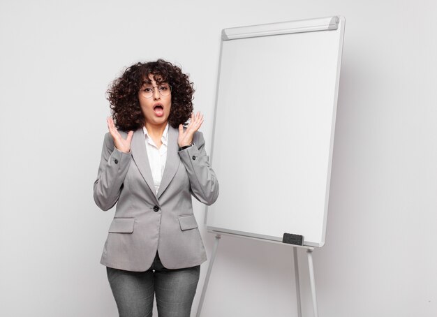 jeune femme d'affaires aux cheveux bouclés et un tableau blanc