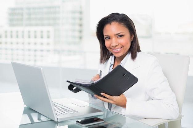 Jeune femme d&#39;affaires aux cheveux sombre naturelle remplissant son horaire