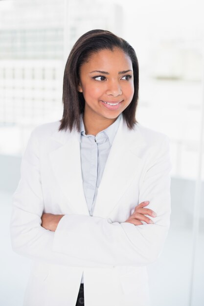 Jeune femme d&#39;affaires aux cheveux sombre posant avec les bras croisés