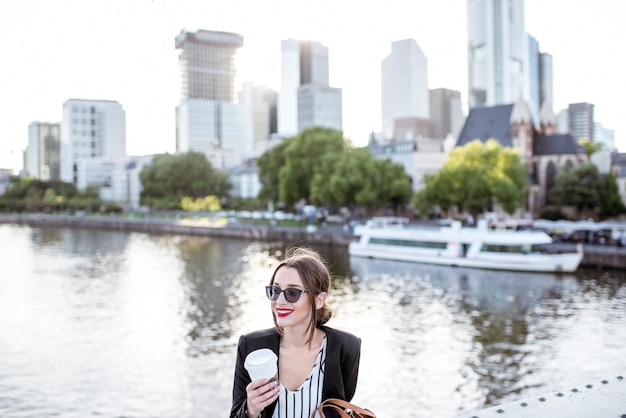 Jeune femme d'affaires ayant une pause-café à l'extérieur assis sur le pont dans la ville de Francfort