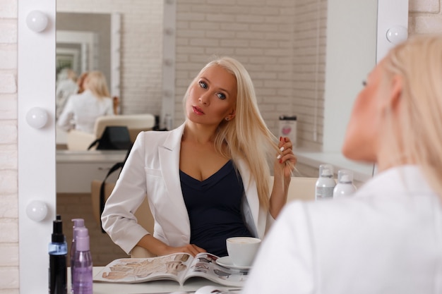 Jeune femme d'affaires de beaux cheveux blonds assis dans un salon de coiffure