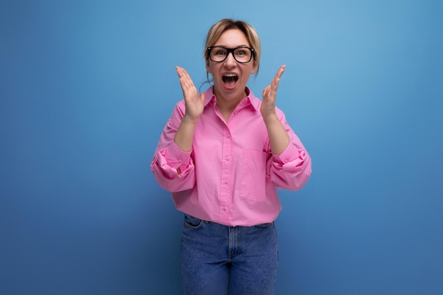 Jeune femme d'affaires blonde confiante européenne positive en chemise rose et jeans sur fond de studio