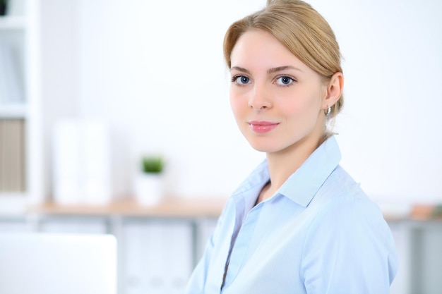 Jeune femme d'affaires blonde avec ordinateur portable au bureau. Notion d'entreprise.