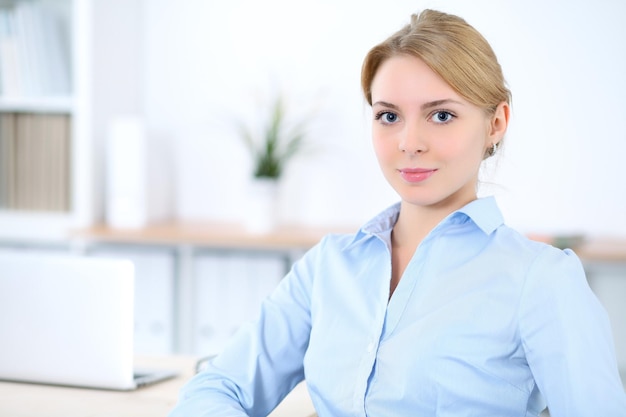 Jeune femme d'affaires blonde avec ordinateur portable au bureau. Notion d'entreprise.