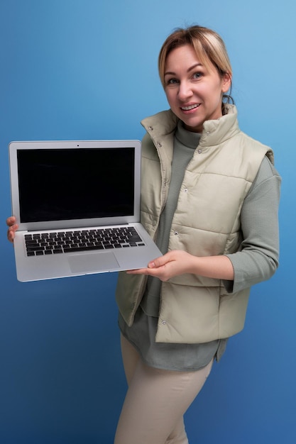 Jeune femme d'affaires blondie avec un ordinateur portable dans ses mains sur un fond bleu