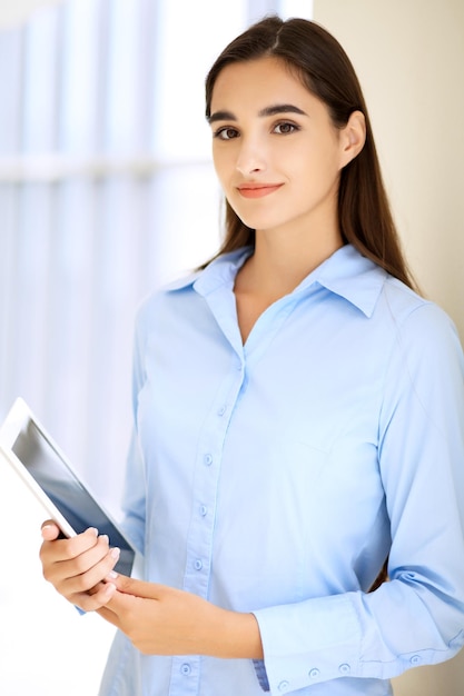 Jeune femme d'affaires brune ou étudiante regardant la caméra