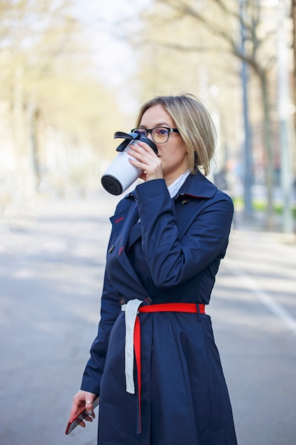 Jeune femme d'affaires buvant du café dans la rue