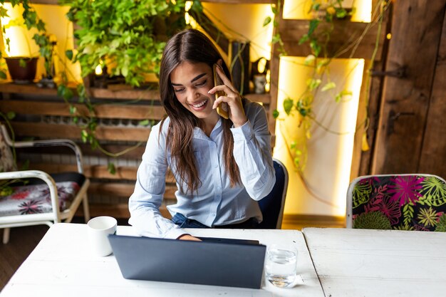 Jeune femme d'affaires buvant du café et utilisant un ordinateur portable au café
