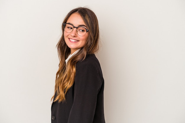 Jeune femme d'affaires caucasienne isolée sur fond blanc regarde de côté souriante, gaie et agréable.